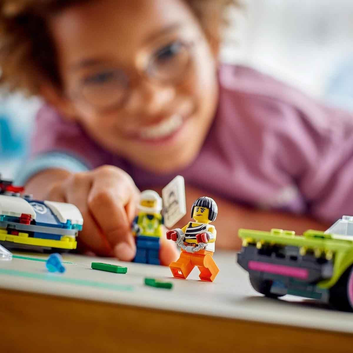 LEGO City Pościg samochodowy z radiowozem i mięśniakiem, zabawkowy pociąg z 2 samochodami wyścigowymi, prezent policyjny dla dzieci, chłopców i dziewcząt od 6 lat, zestaw z policjantem i minifigurkami Ganovinem 60415 Zestawy do budowania Besuche den LEGO-Store